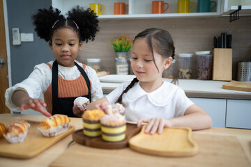 Two happy little kids siblings cooking together, rolling out dough, standing at wooden countertop in modern kitchen homemade.