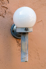 Metal light attached to side of house home or building in the downtown city in late afternoon shade with orange exterior
