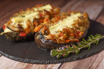 eggplants stuffed with meat and vegetables covered with bechamel sauce on a black slate on a wooden table