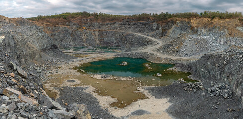 Turquoise lake formed after the process of mining green stone on the mountain. Landscape of rocky mountains and lake at sunset.