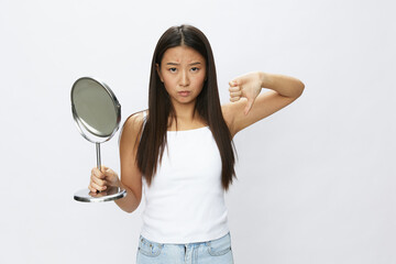 Asian woman with mirror in hand facial skin problems, acne and inflammation, red rash and...