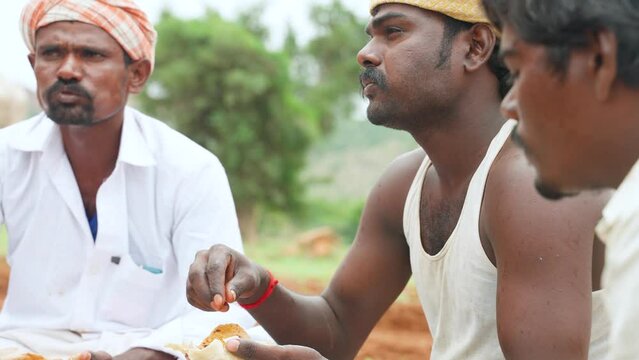 Close up shot of Group of farmers eating lunch while sitting at farmland after work - concept of taking break, cultivation season and farming.