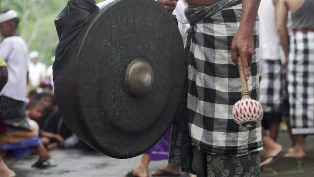 Traditional drum made of metal. Man playing traditional Balinese instrument on the ceremony of Galungan. Playing ethnic drum music. Indonesia, Bali,