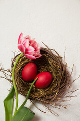 A nest with painted eggs is decorated with beautiful pink tulip
