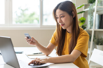 Internet banking, Online shopping at home, asian young woman hand in typing on keyboard, holding credit card, using laptop computer, spending money with purchase on store at home. Shopaholic ecommerce