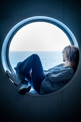 Traveler passenger woman sitting inside a porthole in the boat cruise enjoying the trip and journey...