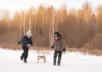 Fototapeta na wymiar Two boys of 8 years old are walking in the forest. Friends cheerfully walk across a snow-covered field. Winter forest in the background. High quality photo