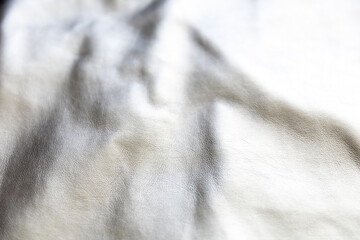 Fototapeta na wymiar Folds on silver metal fabric as abstract background