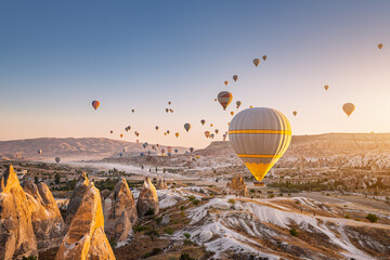 Beautiful panoramic view of the valley in Cappadocia with magical flying balloons and at sunset. Travel and vacation in Turkey. © EdNurg