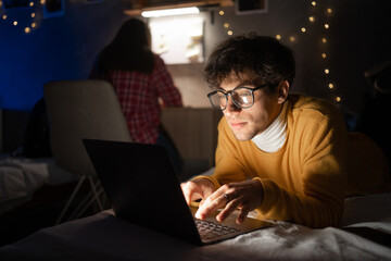 College student studying at night from home in his room.