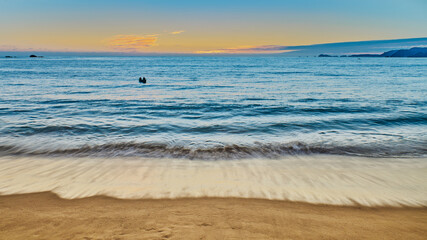 Obraz premium sunset on the beach with sunset and a person in a canoe