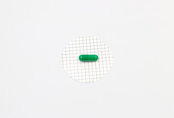 A green pill or medicine on a cross-linked white background