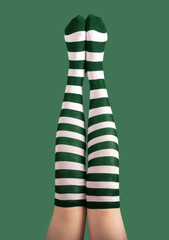 Long sexy female legs stretched high up in striped green and white stockings, tights for St Patrick...