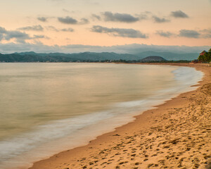 sunset on the beach and the sun is setting on the horizon