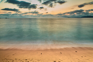 sunset on the beach and the sun is setting on the horizon