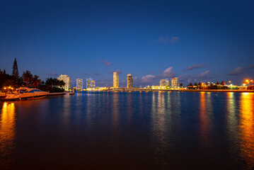 Fototapeta na wymiar View of Miami at sunset, USA. Miami city skyline panorama at dusk with urban skyscrapers and bridge over sea with reflection.