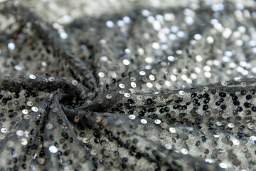 defocused black and silver knitted fabric with sequins and folds texture background	