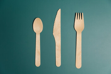 Wooden biodegradable single use utensils on a green background