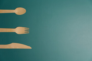 Wooden biodegradable single use utensils on a green background