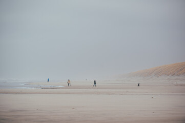 eine einzige kleine Menschengruppe am stürmischen weitläufigen Strand in Dänemark