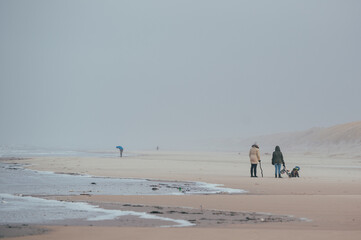 eine einzige kleine Menschengruppe am stürmischen weitläufigen Strand in Dänemark