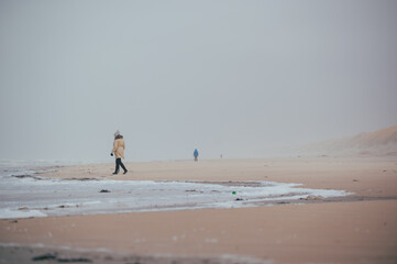 Fototapeta na wymiar eine einzige kleine Menschengruppe am stürmischen weitläufigen Strand in Dänemark
