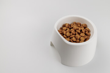白いペット用食器と粒状のペットフード、白背景