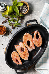 Pieces of fresh salmon fillet with spices on a grill pan. Seafood, culinary background. View from above.
