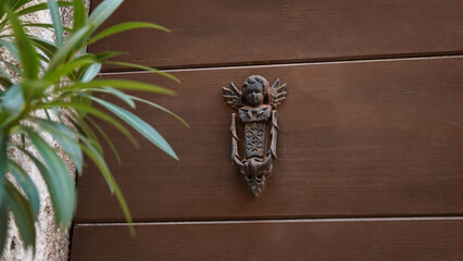 Angel shape door knocker on a brown wooden front door