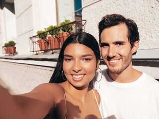 Smiling beautiful woman and her handsome boyfriend. Happy cheerful family. Sexy couple posing in the street at sunrise. During romantic date at sunny summer day outdoors. Taking pov selfie photos