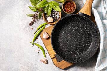 Empty skillet, vegetables, spices and herbs on gray stone background. Food cooking background with Frying pan. View from above. Copy space.