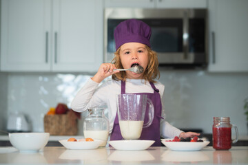 Chef child cooking healthy meal and dinner preparation. Kids are preparing the dough, bake cookies in the kitchen, lick spoon .