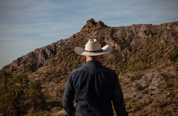 Adult man in cowboy hat against mountain and sky. Almeria, Spain