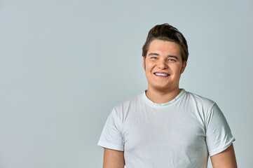 A man in a white T-shirt on a gray background smiles