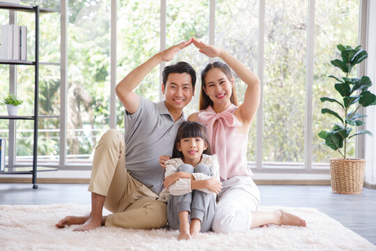 Real estate and mortgage concept : Family with child having fun in new home. Joyful first-time buyers in living room. Real estate, residential mortgage, moving into dream house.