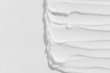 The texture of the white cream. Cosmetic background. Smears of body care cosmetics on a white background. Wellness and beauty concept. Top view.