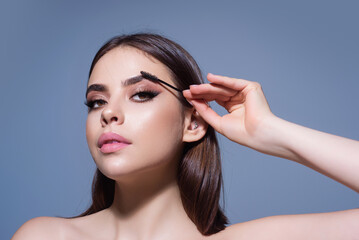 Eyebrow shaping, woman combs eyebrows with a brus. Eyebrow line. Makeup and cosmetology concept. Female model with long eyelashes and thick eyebrows. Perfect shaped brow.