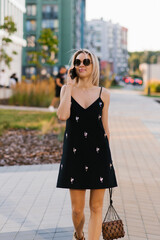 Fototapeta premium Young happy woman is walking around the city, talking on a mobile phone.