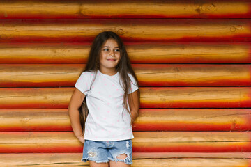 Beautiful cute baby girl posing on the background of a log wall