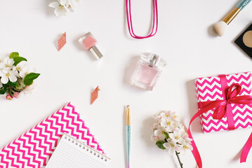 Concept of a beauty blog. Accessories for women's makeup and delicate apple blossoms on a white background. Flat apartment, top view, women's desk, workplace with notebooks in pink