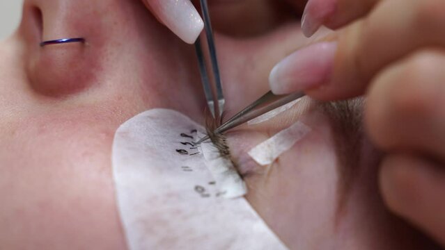 Eyelash extension procedure. Woman eye with long eyelashes. Eyelashes, close-up, macro, selective focus. 4K