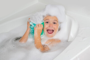 Kids face in foam. Kid in a bath tub. Washing in bath with soap suds on hair. Child taking bath....