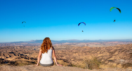 woman looking at paraglider in the desert ( Gorafe in Spain)