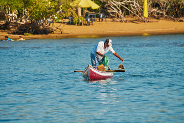 fisherman in his canoe using a net to fish in the middle of the sea