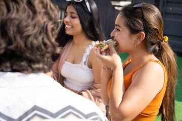 Group of cheerful young indian friends girls having fun eating pizza talking and laughing together at restaurant cafe. Summer season, food and drinks. Fast food. Selective focus.