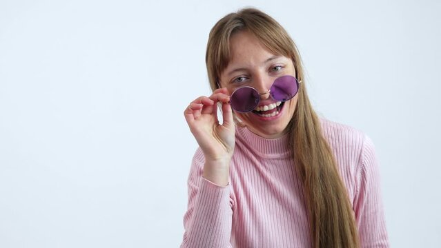 Fashion Model Looking Over The Purple Glasses And Smiling. Isolated Slow Motion Shot 