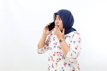 Shocked asian muslim woman standing while talking on the phone. Isolated on white background