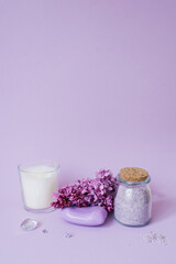 Cosmetics, soap and bath salts and lilac flowers on the background, an even layer. Copy space