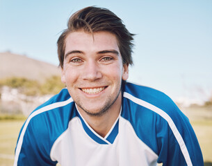 Football player, portrait and smile on field for training, fitness and workout goals, mission and strategy on blue sky. Happy soccer athlete, person or man face for contest, game and outdoor sports © C. D./peopleimages.com