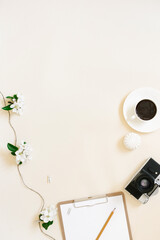 Vintage retro camera and white apple blossoms with a clean tablet and pen on a beige background. Feminine blogger flat lay. top view from copy space. Spring concept layout.